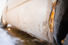 Rusted Fender Of A White Car Close-up. The Effect Of Reagents In Winter On An Unprotected Car Body. Rotten Metal
