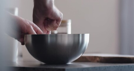 Wall Mural - Slow motion man making granola mix cereal flakes in steel bowl on kitchen countertop