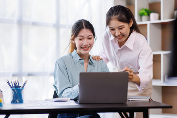 Checking the numbers. Team of Asian young business people analyzing data using a computer while talking about marketing strategy and planning working in the office