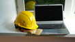 © Oksava - A yellow hard hat of a builder, a paint brush and a laptop on the windowsill.