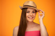 Young woman with bare sholders touching her Mexican hat. Isolated face portrait on orange yellow background.