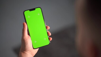 A man's hand is holding a smartphone with the vertical screen visible. guy hand holding a mobile phone with a green screen for keying and tracking