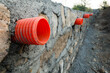 A row of orange culverts or water outlet pipes through a stone retaining wall for storm drainage in the hills of Uttarakhand India.