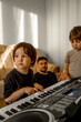 © Anastasia Amraeva - The boy is learning to play the synthesizer. In the background, a family listens to a child playing a musical instrument. The concept of music education.