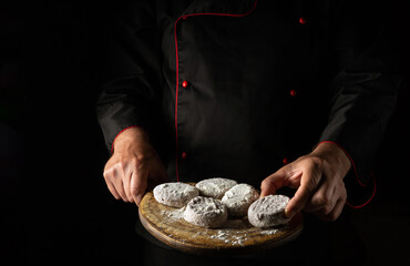 Meat burgers with veal or cutlets in the form of cutlet on a cutting board in the hands of the chef. Free space for advertising on a dark background.