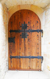 Fototapeta Desenie - Old wooden door with round arch and metal decorations. Antique castle door from the Middle Ages.
