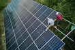 © anatoliy_gleb - Aerial view of men technicians installing solar panels to high steel platform. Concept of alternative energy.