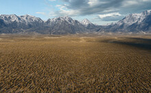 Grassland Plain With Mountains On The Horizon Under A Blue Cloudy Sky. 3D Render.