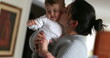 © Marco - Casual mother holding and loving baby. Mom kissing infant boy at home indoors. Real life love and cuddle