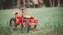 Beautiful Classic Red Tricycle. For The Children In The Middle Of The Green Lawn Classic Bicycle Old Bicycle For Greeting Card Postcard. With Copy Space