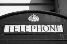 Vintage Style Phone Booth Sign. Classic English Phone Box. Black And White Image. Public Phone Kiosk In City Of London