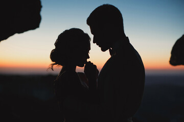 Moonlight highlights the silhouettes of the bride and groom in the mountains