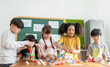 © eggeeggjiew - Group Of Multi ethnic Elementary School Pupils playing wooden block toys in Classroom together, Indoor activity.