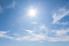 Hot Sparkle Sun On Blue Cloudy Sky Background