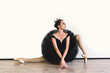 © Nick ALDI - ballerina in black swan dress against white background. Young ballet dancer practicing before performance in black tutu, classical dance studio, copy space