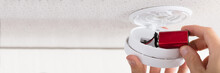 Person's Hand Inserting Battery In Smoke Detector
