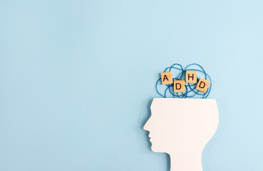 Silhouette of human head and wooden blocks with the letters ADHD on pastel background. Creative concept of attention deficit hyperactivity syndrome. Copy space