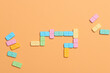 © Marc Tran/Stocksy - Dominoes. Colorful domino chips lay on a beige background