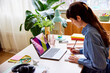 © ALTO IMAGES/Stocksy - Woman writing in notepad while working on laptop