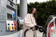 © McKinsey Jordan/Stocksy - Young Woman Smiles As She Fills Her Vehicle With Gas