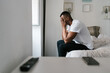 © Ezequiel Giménez/Stocksy - Tired black man covering face and sitting on bed