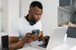 © Ezequiel Giménez/Stocksy - Attentive man working on laptop and using smartphone