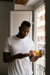 © Ezequiel Giménez/Stocksy - Black guy with glass of juice using smartphone