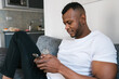 © Ezequiel Giménez/Stocksy - Black male browsing smartphone at home