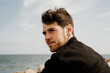 © Alba Vitta/Stocksy - Portrait of handsome man  outdoors by the beach