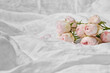 © Yaroslav Danylchenko/Stocksy - Pink tender roses lying on bed with crumpled sheet