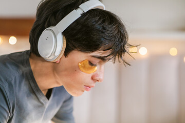 Teen boy with eye patch and headphones indoor