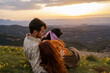 © Alba Vitta/Stocksy - Portrait of young loving couple in the mountain at sunset with dog