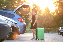 Young Female Driver Putting Luggage Suitcase Bag Inside Her Car. Travelling And Vacations Concept