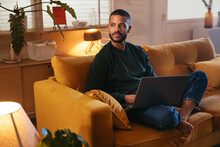 African American Man Using Laptop On Sofa