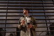© Alba Vitta/Stocksy - Young man with coffee and smartphone by the city