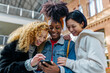 © VICTOR TORRES/Stocksy - Cheerful multiethnic friends browsing smartphone in train station