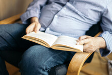 Unrecognizable Man Reading A Book In An Armchair