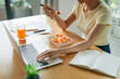 © Marc Tran/Stocksy - Smiling businesswoman having healthy lunch at workplace