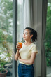 © Marc Tran/Stocksy - Smiling elegant businesswoman in bright office drinking orange juice