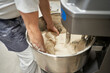© Javier Díez/Stocksy - Crop baker mixing dough in machine