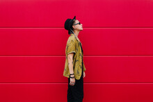 Stylish Woman In Trendy Outfit And Hat On Red Background