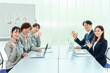 © buritora - 会議をする作業着姿・スーツ姿の会社員（カメラ目線）
