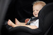 Funny baby boy in a car seat. Thoughtful child sits in the car. Passenger safety concept