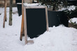 A vintage clean black wooden billboard stands on a winter snowy road. The concept of outdoor advertising for cafes and shops. Copy space, layout.