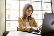 © Lomb - Japanese businesswoman typing on her laptop computer sitting in the office desk against a big window - business, finance and technology concept