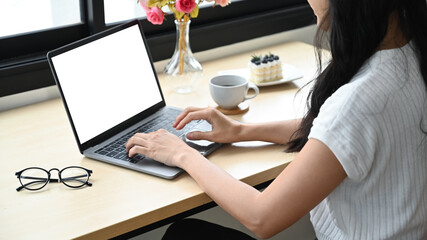 Cropped shot creative female employee using laptop computer at modern workplace