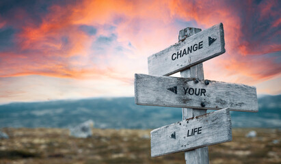 change your life text quote caption on wooden signpost outdoors in nature with dramatic sunset skies. Panorama crop. new beginning concept.