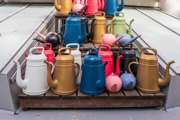 Wall Mural - Different sizes of different colors of watering cans for sale in a flower shop