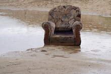 Old Armchair Stands In A Puddle Of Water During The Rain. Autumn Season. Beyond Repair