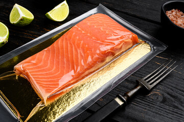 Wall Mural - Salmon fillets in a vacuum package, with herbs, on black wooden table background